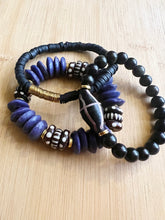 Load image into Gallery viewer, A fun and edgy purple and black stack featuring a purple ashanti glass bracelet with with black and white dotted bone beads, and black polymer clay bracelet and a onyx bracelet with unique black and gold focal bead All bracelets measure 7 inches but can be customized upon request
