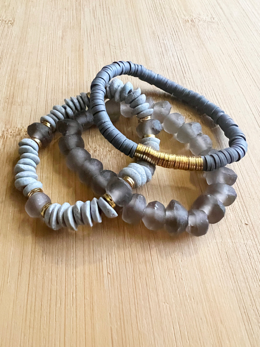 For the neutral lover, a grey stack featuring a grey ashanti glass bracelet with with smokey grey recycled glass beads, and grey polymer clay bracelet and a grey recycled glass bracelet  All bracelets measure 7 inches but can be customized upon request