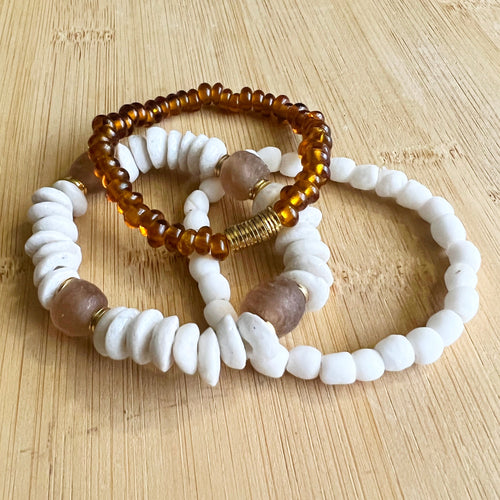 A perfectly neutral stack of white and amber, featuring a white ashanti glass bracelet with with recycled glass beads, and white recycled glass bracelet and an amber glass bracelet  All bracelets measure 7 inches but can be customized upon request
