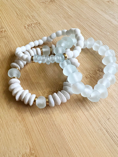With all the salty seaside vibes, a white and seaglass stack featuring a white ashanti glass bracelet with with recycled glass beads, and white glass bracelet with small green glass focal beads and a seafoam recycled glass bracelet  All bracelets measure 7 inches but can be customized upon request