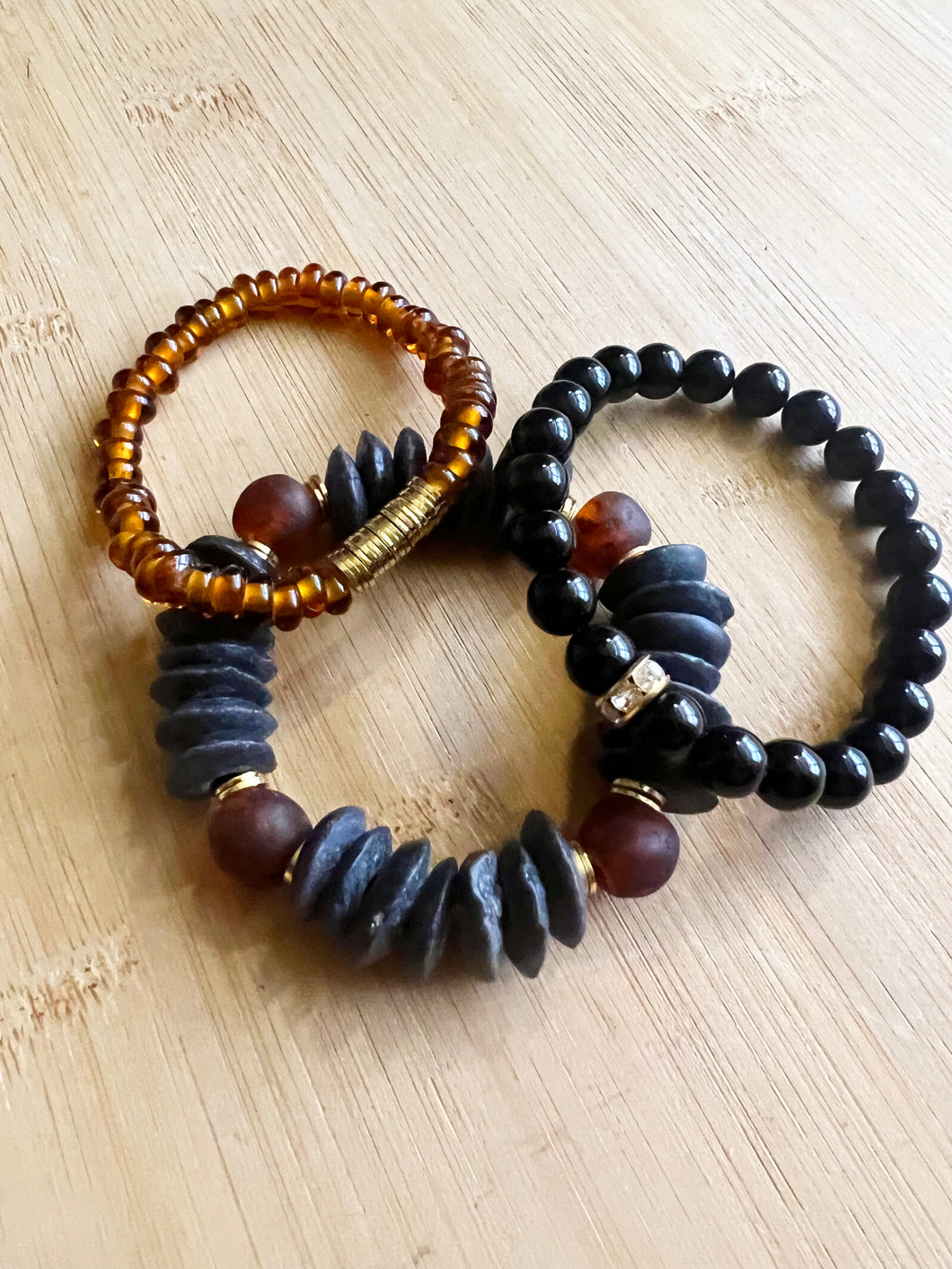 The edgy combo of black and amber creates a unique and gorgeous stack.  Features a black ashanti glass bracelet with with recycled glass beads, an amber glass bracelet with brushed gold accents and an onyx bracelet with small gold and crystal accent bead  All bracelets measure 7 inches but can be customized upon request