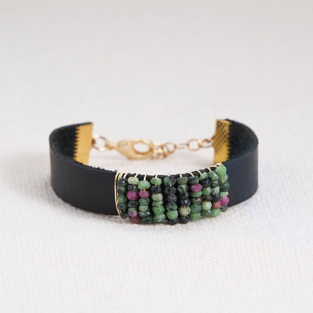 Absolutely stunning ruby zioste faceted stones hand wrapped with 14kt gold filled wire on a black leather cuff with a gold filled lobster claw and chain closure.   