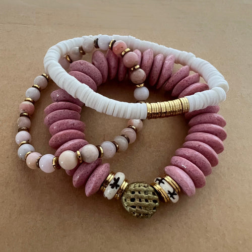 A perfect pop of pink, this stack features a pink ashanti glass bracelet with carved star bone beads and an African brass focal bead, and white polymer clay bracelet and a pink peruvian opal bracelet   All bracelets measure 7 inches but can be customized upon request 