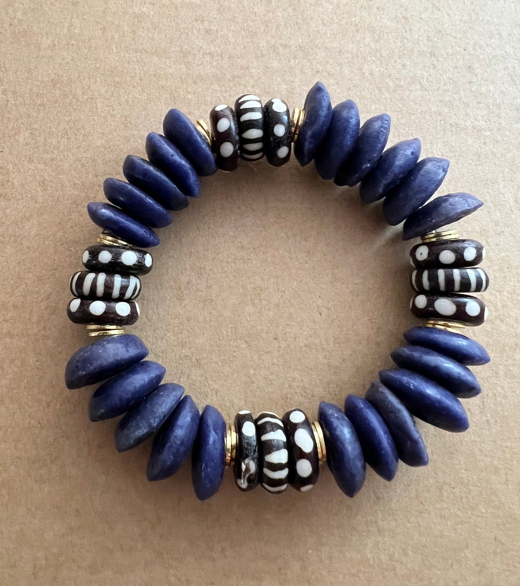 For a touch of purple in your stack this bracelet features dark purple Ashanti beads and black and white bone beads with brushed gold accents  Our bracelets are 7