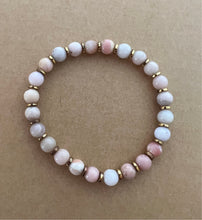 Load image into Gallery viewer, A perfect pop of pink, this stack features a pink ashanti glass bracelet with carved star bone beads and an African brass focal bead, and white polymer clay bracelet and a pink peruvian opal bracelet   All bracelets measure 7 inches but can be customized upon request 
